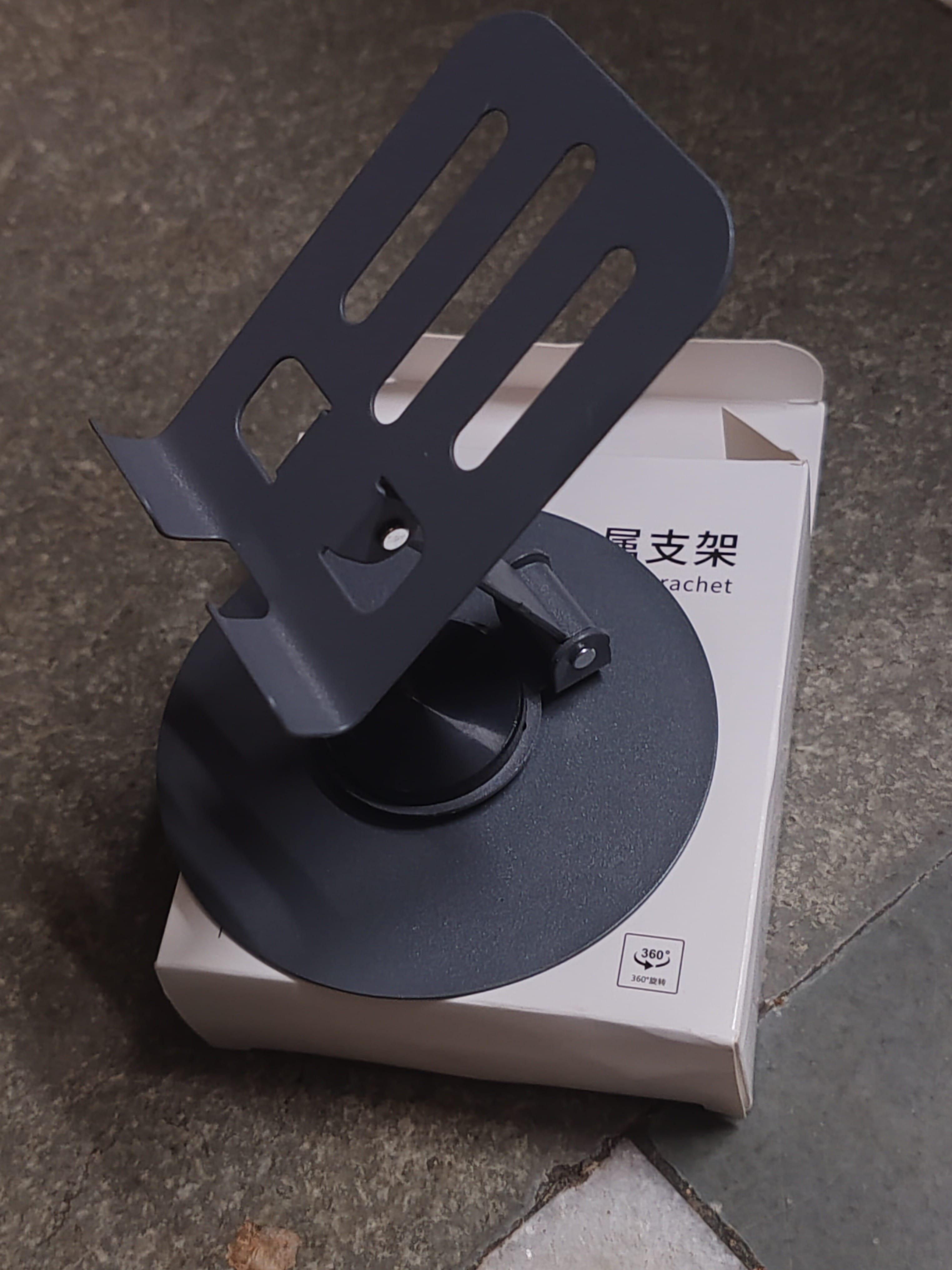 Black phone holder on a white box with text on a dark surface