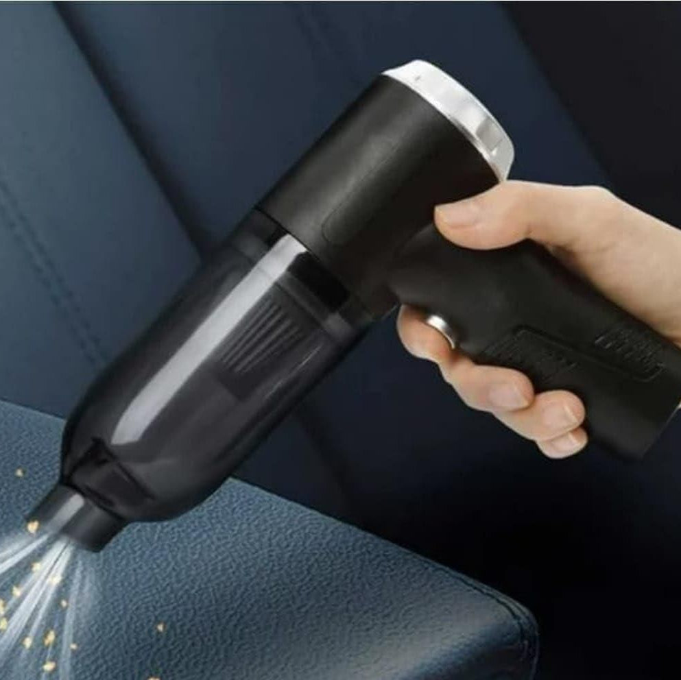 Hand holding a black handheld vacuum cleaner cleaning a car seat.